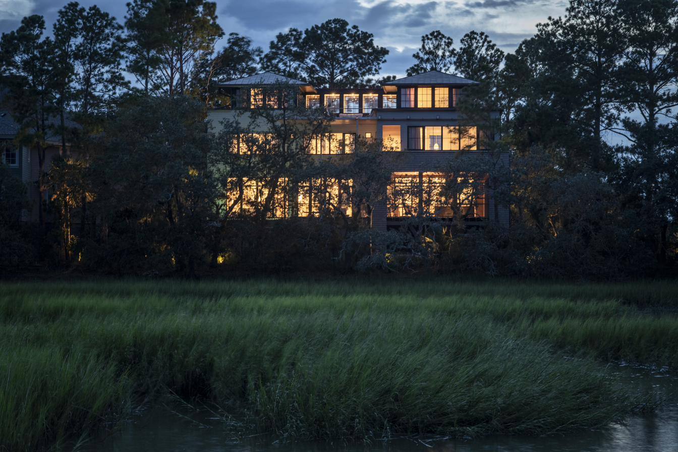 Henselstone residence at dusk with warm-lit windows over the marsh