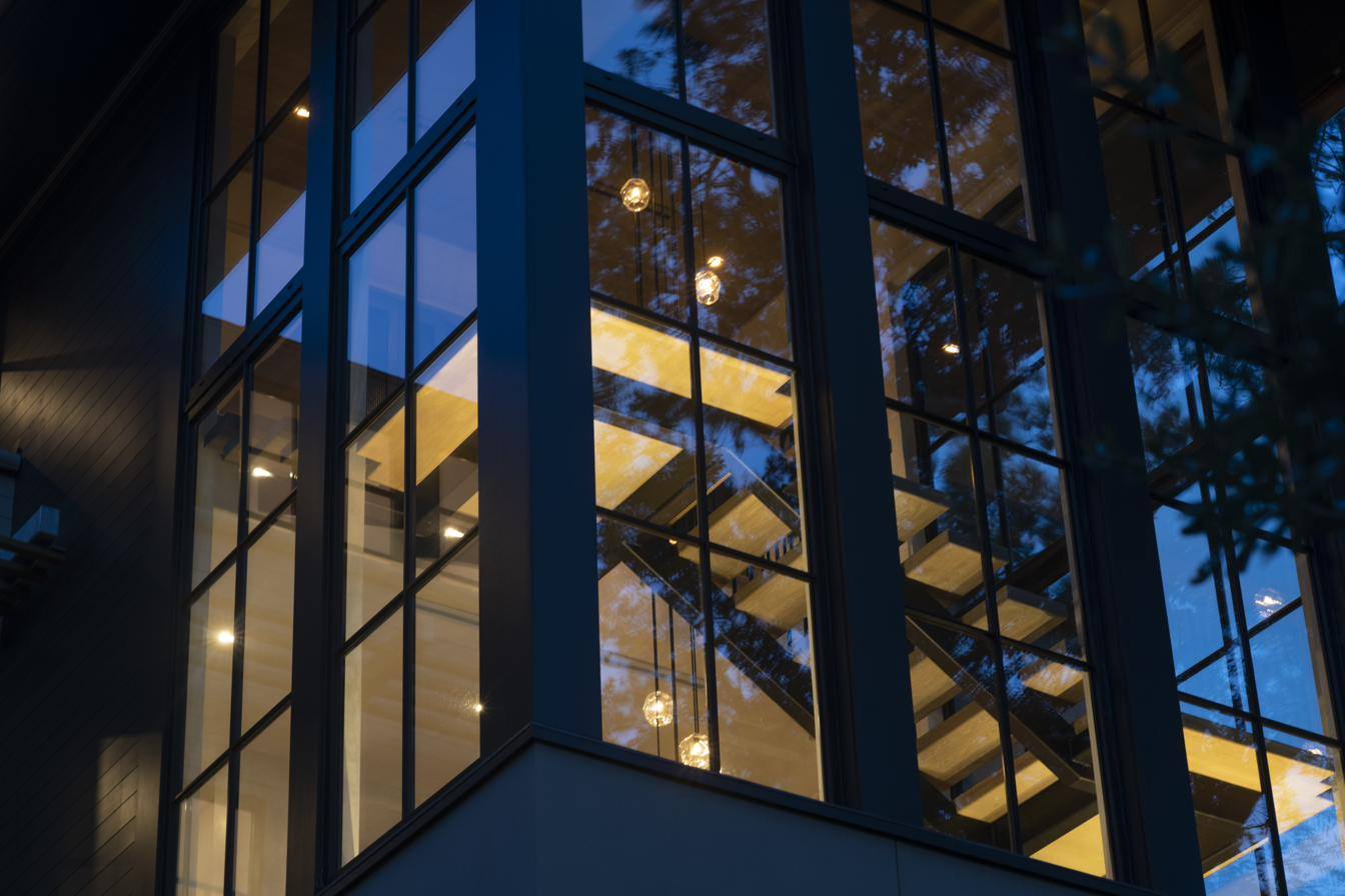 Dusk view of a Henselstone corner curtain wall with a glowing timber staircase inside